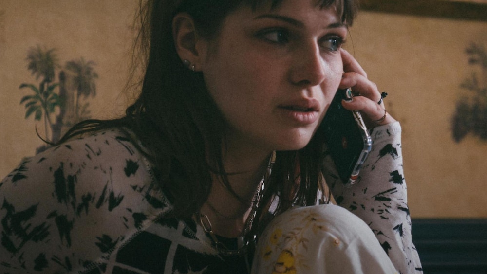 K-FILMS AMÉRIQUE Une fille pleure au téléphone assise dans un lit.