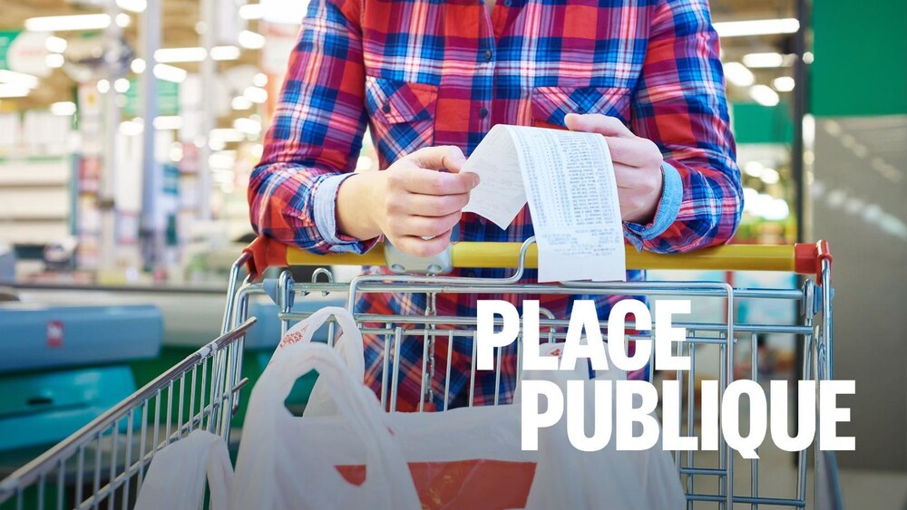 Une femme appuyée sur un panier d'épicerie. Elle tient un reçu d'achat.