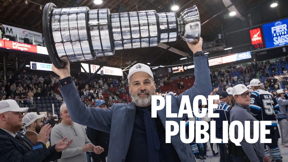 Yanick Jean soulève le trophée Gilles-Courteau sur une patinoire remplie de monde.