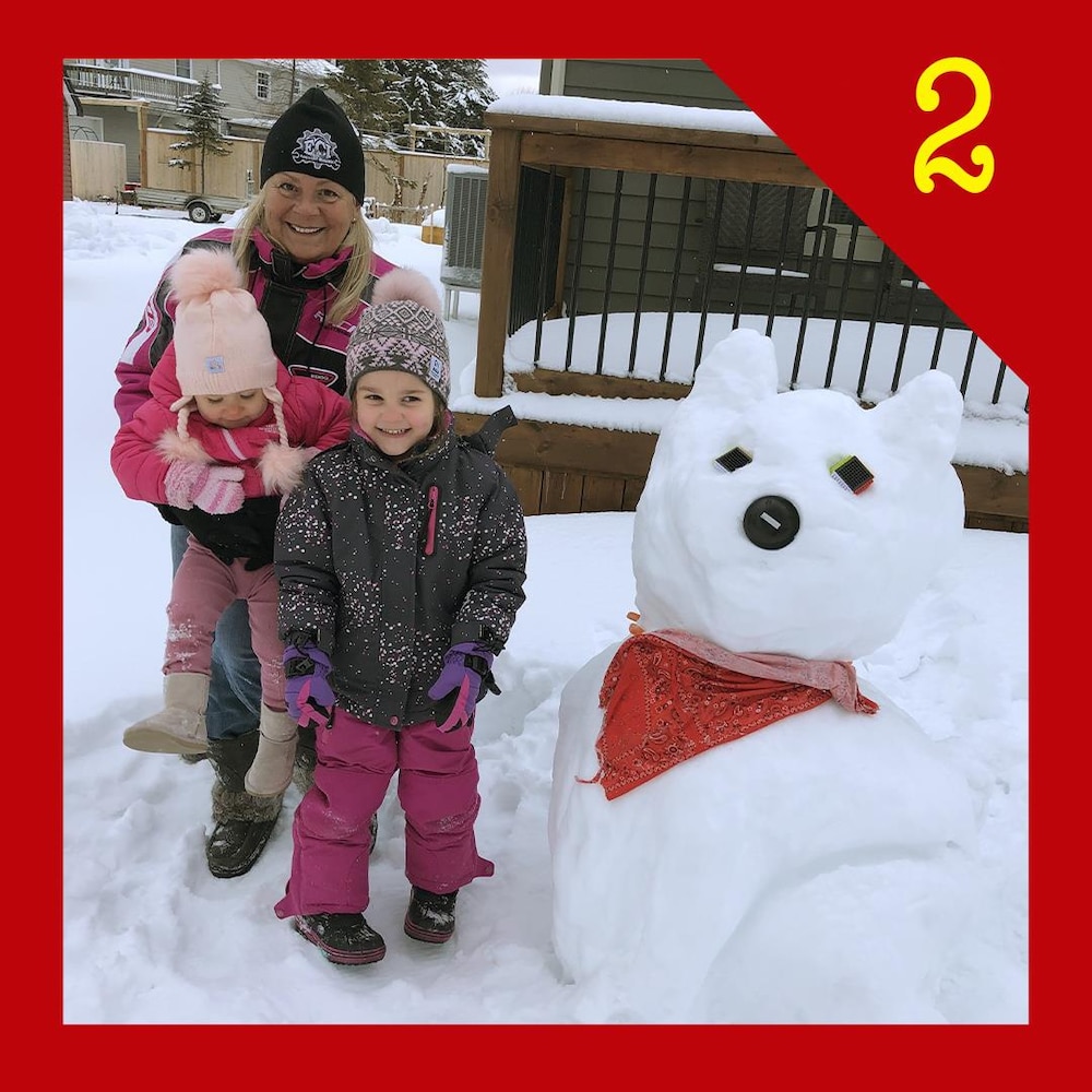 Trois personnes devant un bonhomme de neige.