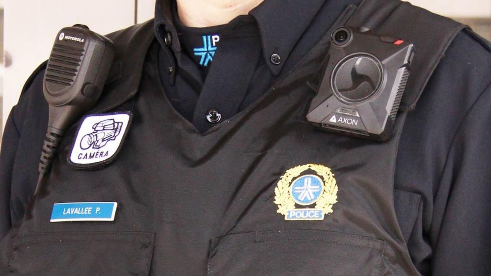 Un policier du SPVM porte une caméra portative à la gauche de sa veste, au-dessus de son insigne.