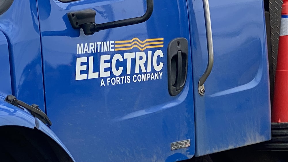 La portière bleue d'un camion. Les mots « Maritime Electric A Fortis Company » sont écrits en lettres blanches.