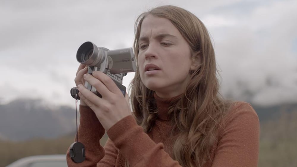 Une femme regarde le moniteur d'une caméra vidéo.