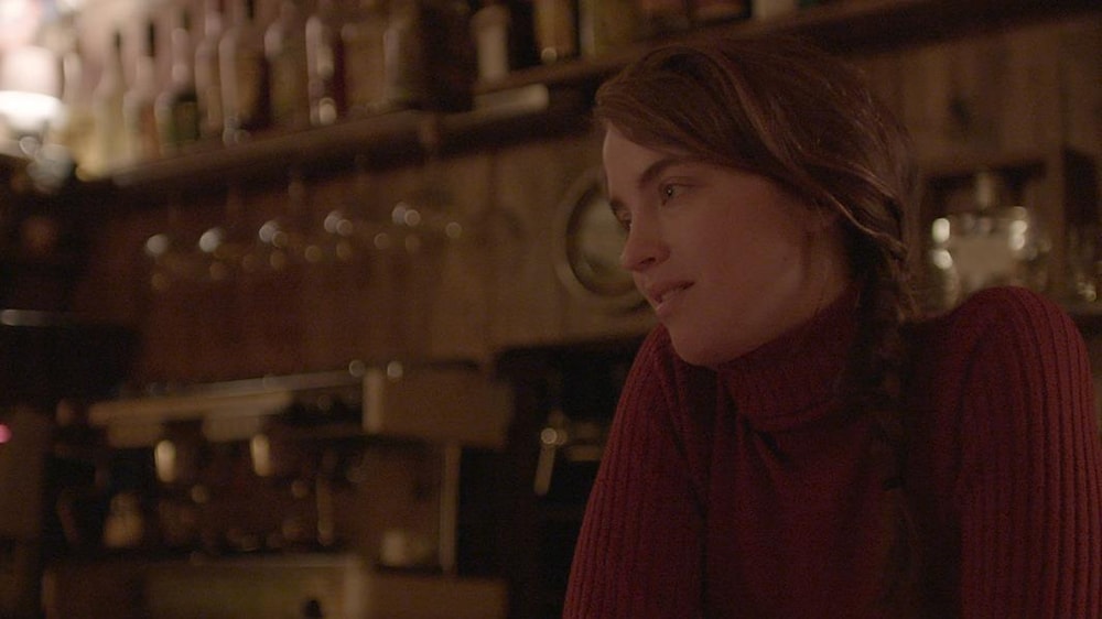 Une femme est assise dans un bar et regarde vers la gauche
