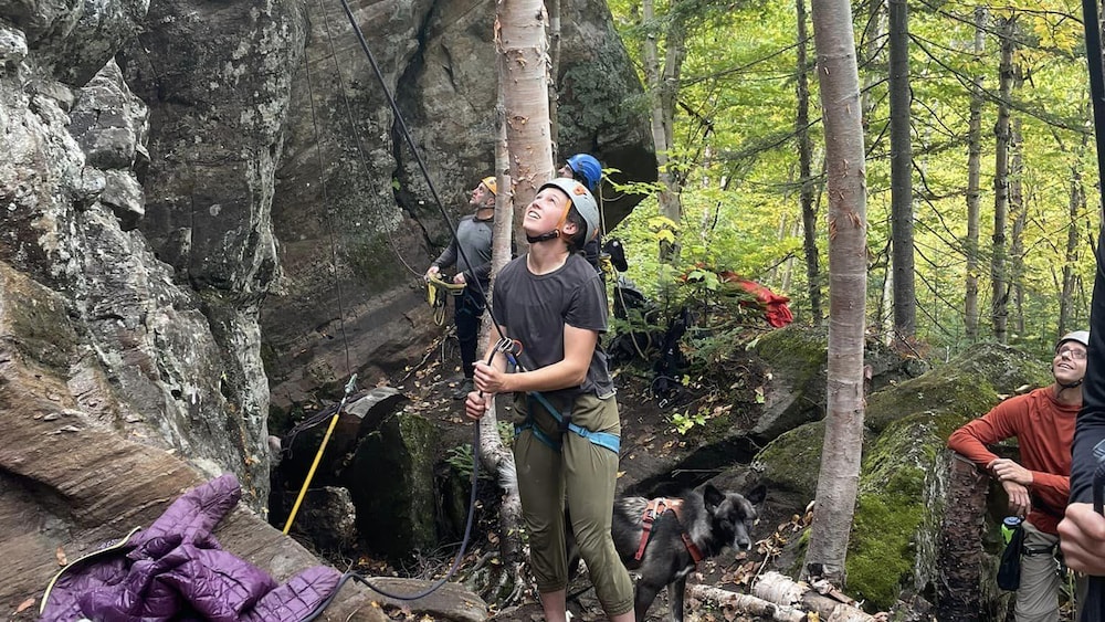 Une femme pratique l'escalade en extérieur et assure son partenaire.
