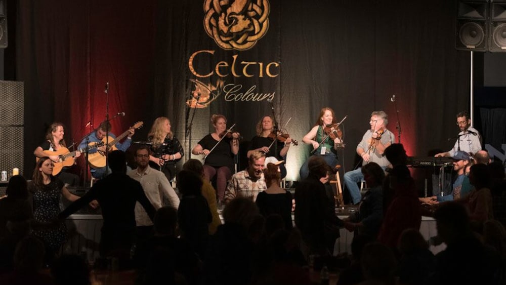 Des danseurs devant des joueurs de violon.
