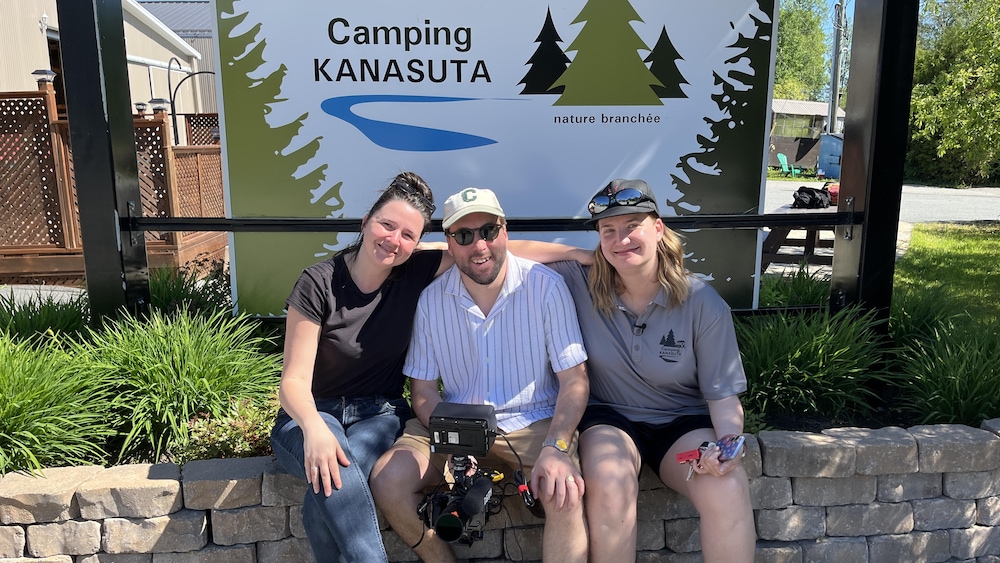 Jessica Gélinas, Simon Beaudry et Sara Karel Chiasson posent devant l'affiche du Camping Kanasuta.