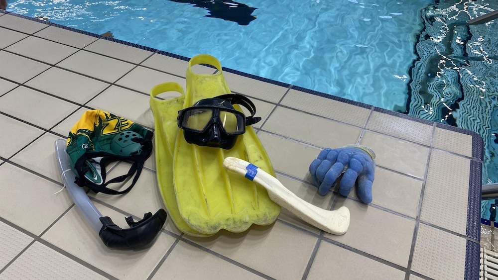 Des palmes, un masque, un bâton et un gant, ainsi qu'un tuba rattaché à un casque de bain avec protection aux oreilles.