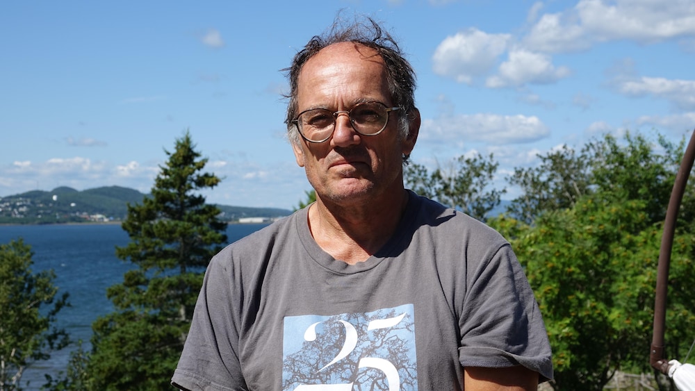 Jean-Marc Beaulieu photographié à Miguasha, avec le paysage de Dalhousie et la baie des Chaleurs derrière.