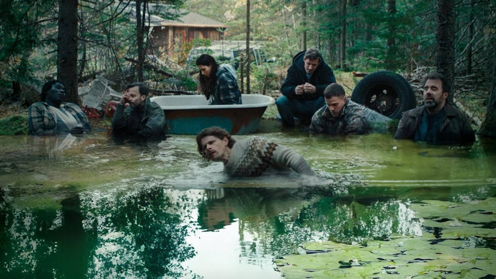 Affiche du film montrant ses protagonistes dans un marécage au beau milieu d'une forêt, non loin d'une cabine en bois. 
