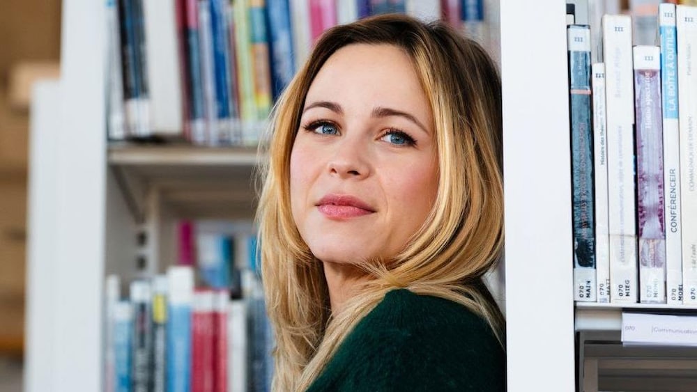 Une femme dans les rangées de livres d'une bibliothèque.