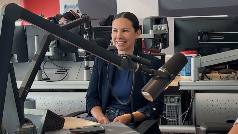 Une femme souriante est assise en studio et parle au micro.