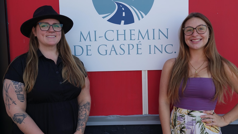Deux femmes devant la pancarte Mi-Chemin de Gaspé.