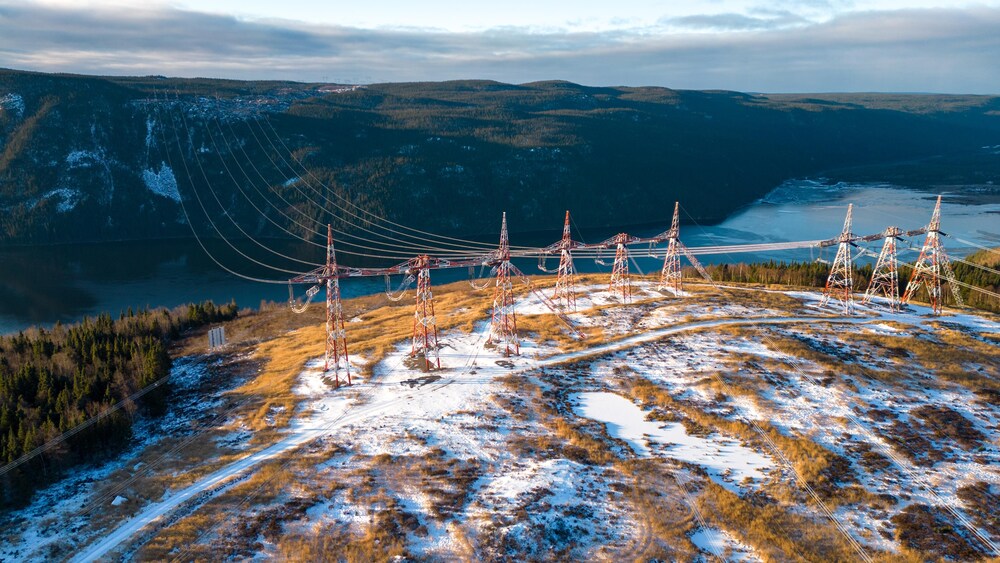 Des lignes électriques traversent un fleuve pendant l'hiver.