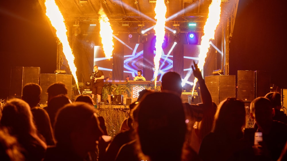 Des festivaliers dansent devant une scène ou il y a un dj.
