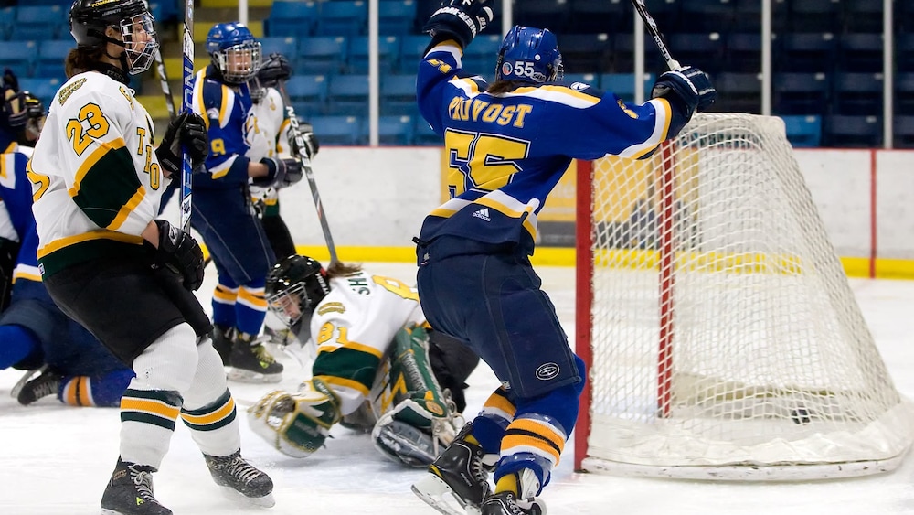 Mariève Provost, portant le numéro 55 des Aigles Bleues, lève son bâton pour célébrer un but au hockey féminin.