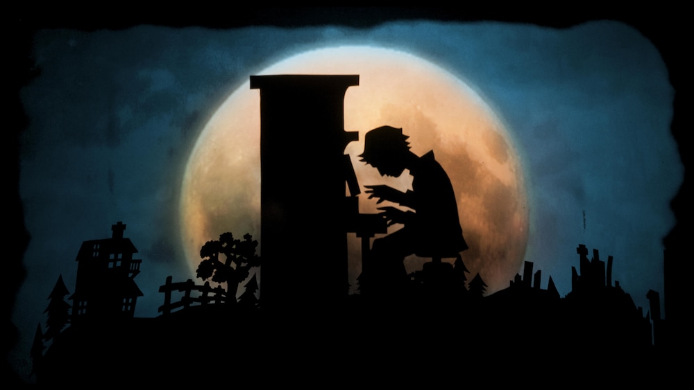 Extrait du spectacle de marionnette «Le piano à voile». Dans un jeu d'ombres, le profil d'un jeune garçon jouant du piano se découpe devant la lune.
