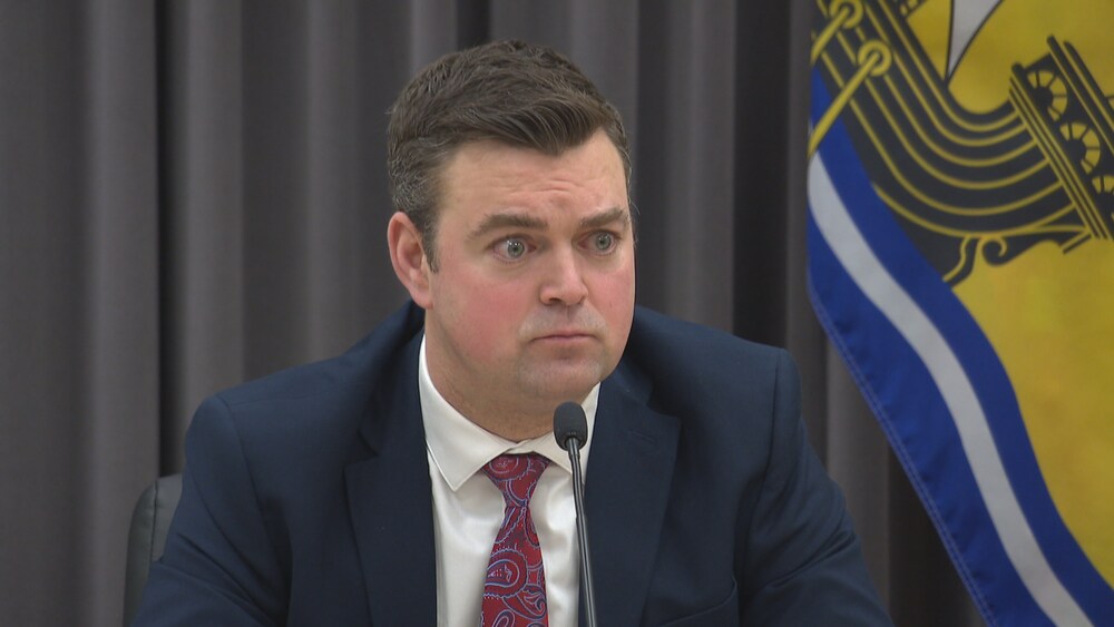 Rob McKee en conférence de presse devant un micro. 