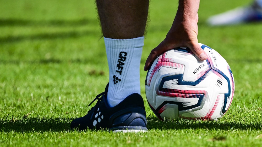 Une balle de soccer à côté du pied d'un joueur.
