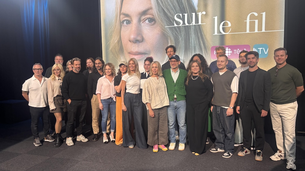 Radio-Canada / Charles Rioux Les acteurs et les producteurs posent devant une affiche de la série.