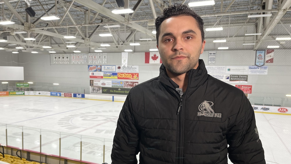 Tanner Doiron regarde la caméra. Il est debout dans des gradins. L'une des patinoires de l'Université de l'Île-du-Prince-Édouard est derrière lui.