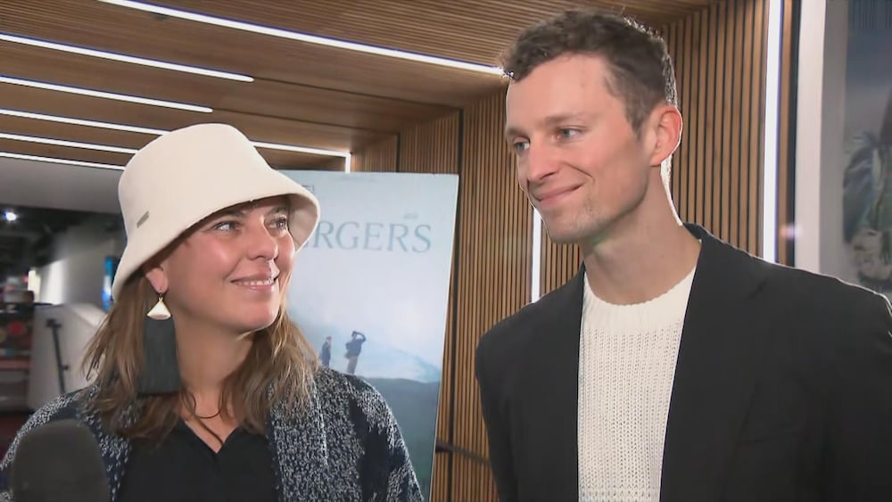Radio-Canada Une femme et un homme accordent une entrevue dans le hall d'un cinéma.