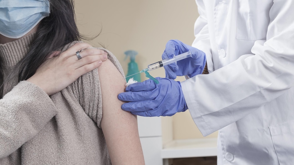Une femme reçoit une dose de vaccin dans son bras gauche.