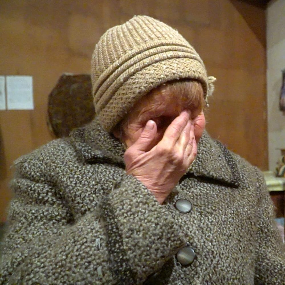 Ludmila, la main sur le visage, pleure.