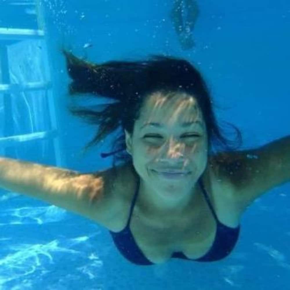 Alexandra nage en souriant, sous l'eau.