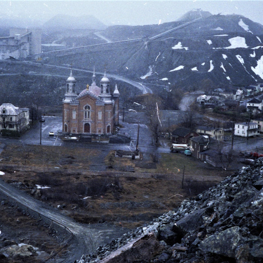 Photo couleur de l'église et des maisons du quartier Saint-Maurice entourées de monticules.
