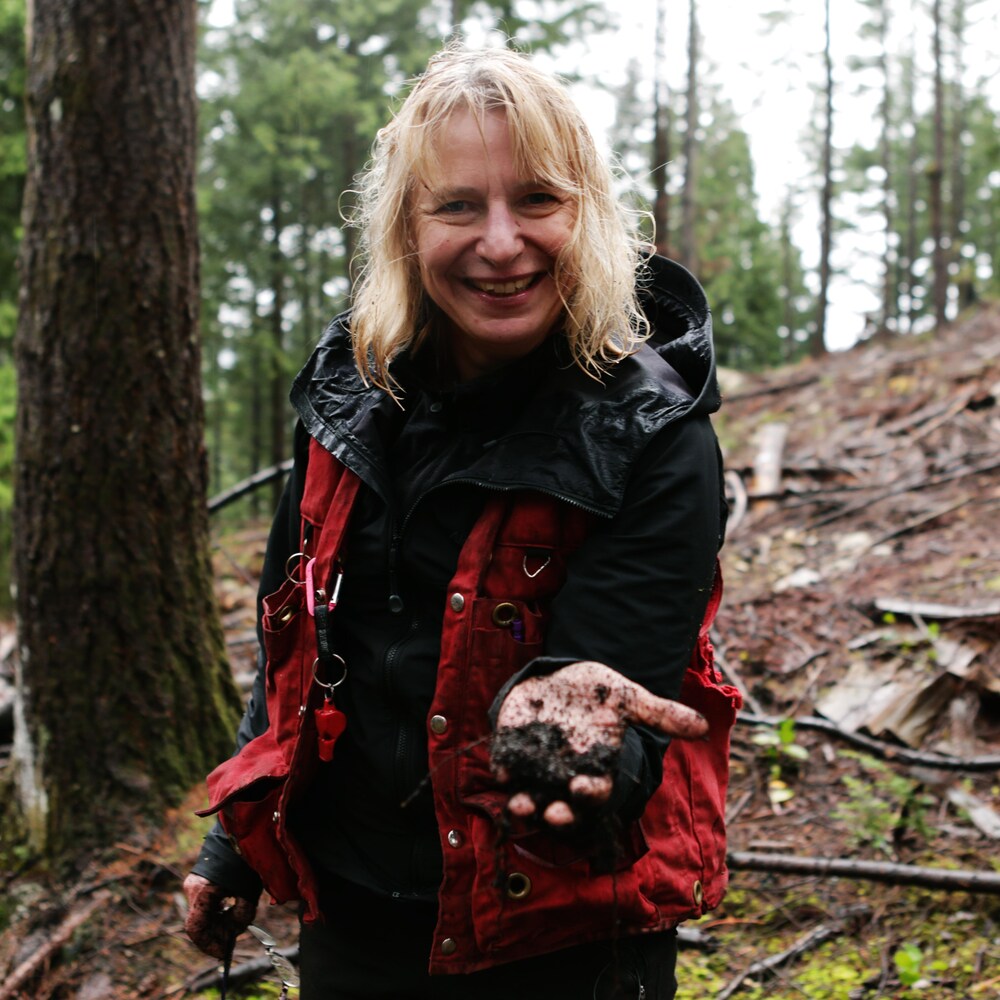 Une femme dans une forêt nous montre de la terre