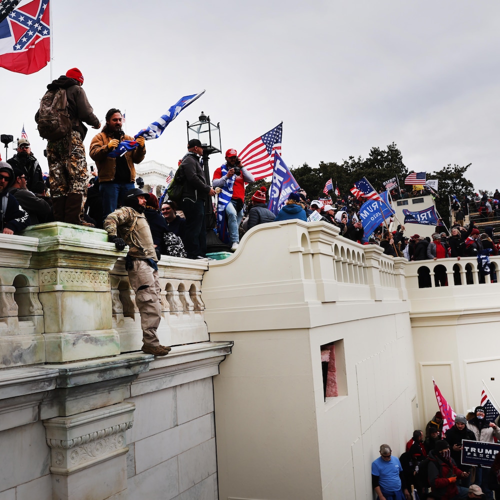 Des partisans de Donald Trump, à l'extérieur du Capitole, certains portant des drapeaux américains ou pro-Trump.