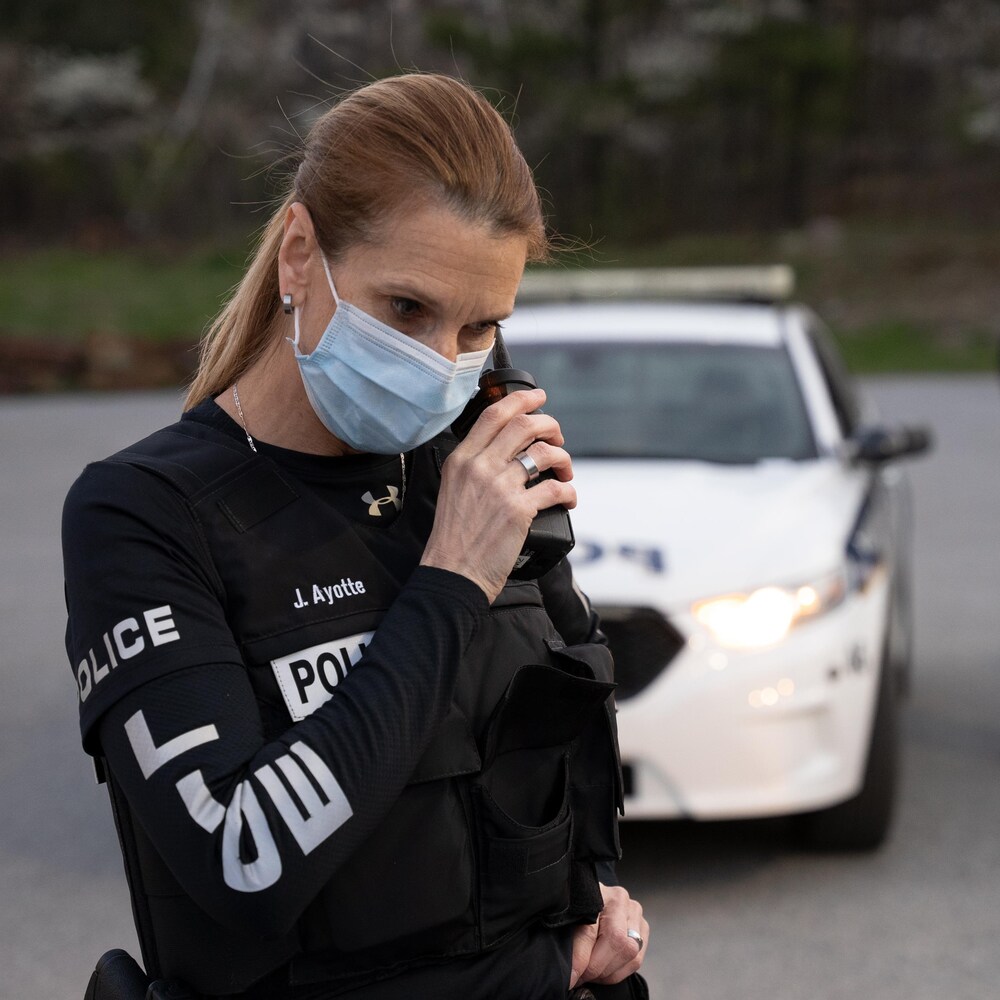 Une policière vêtue d'un gilet pare-balles parle dans une radio portative.