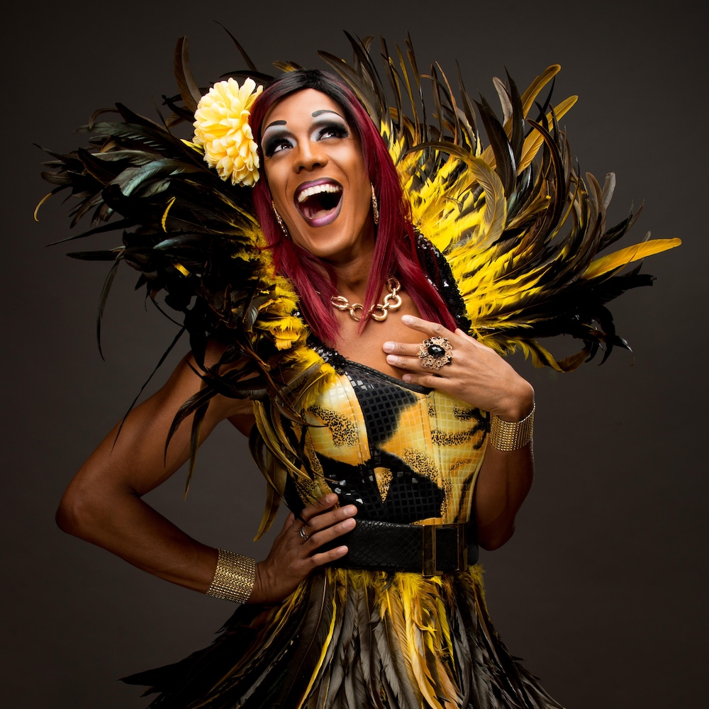 Barbada pose dans un costume de plumes noires et jaunes avec une fleur sur la tête.