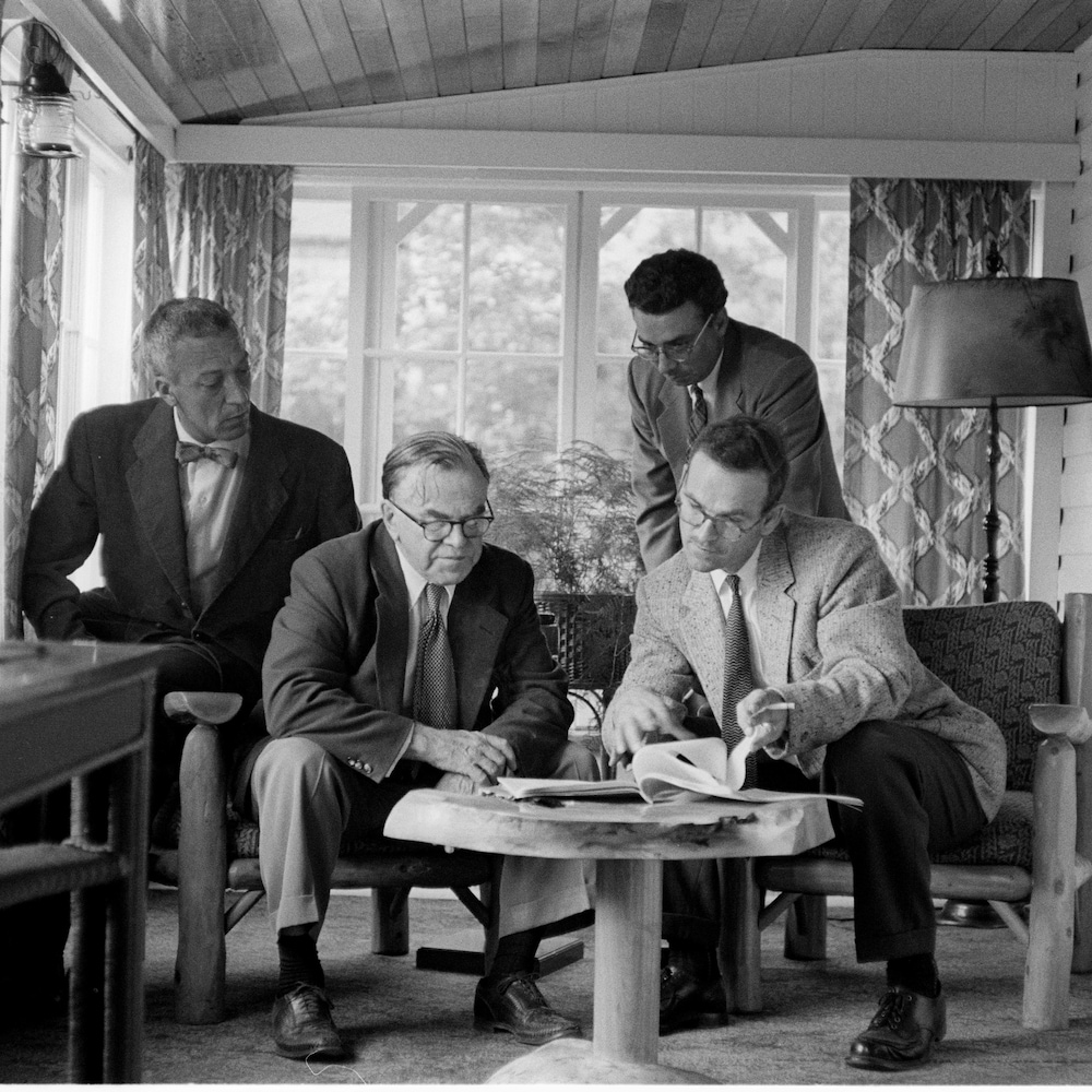 Claude-Henri Grignon et François Quirion regardent des textes sur une véranda, deux autres hommes sont avec eux.