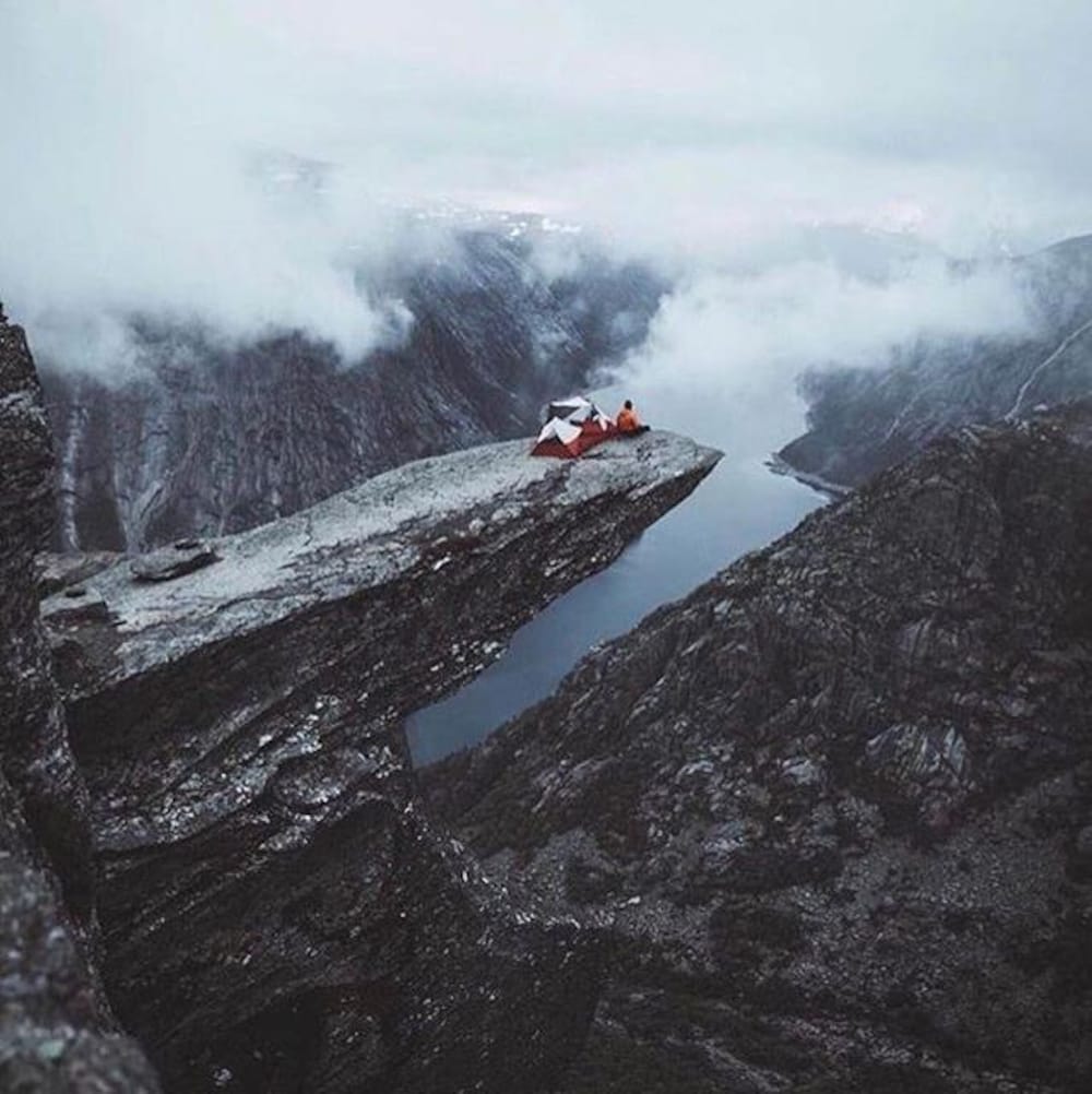 Une personne a installé une tente au bout du pic rocheux de Trolltunga en Norvège.
