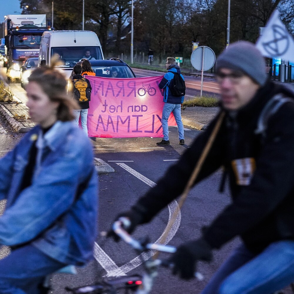 Des militants bloquent la circulation automobile avec des banderoles colorées.