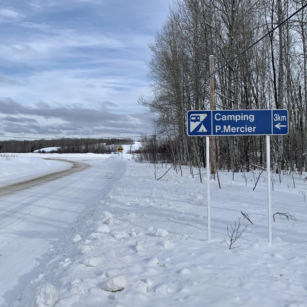 Une pancarte près d'un chemin indique que le Camping Mercier est à trois kilomètres.