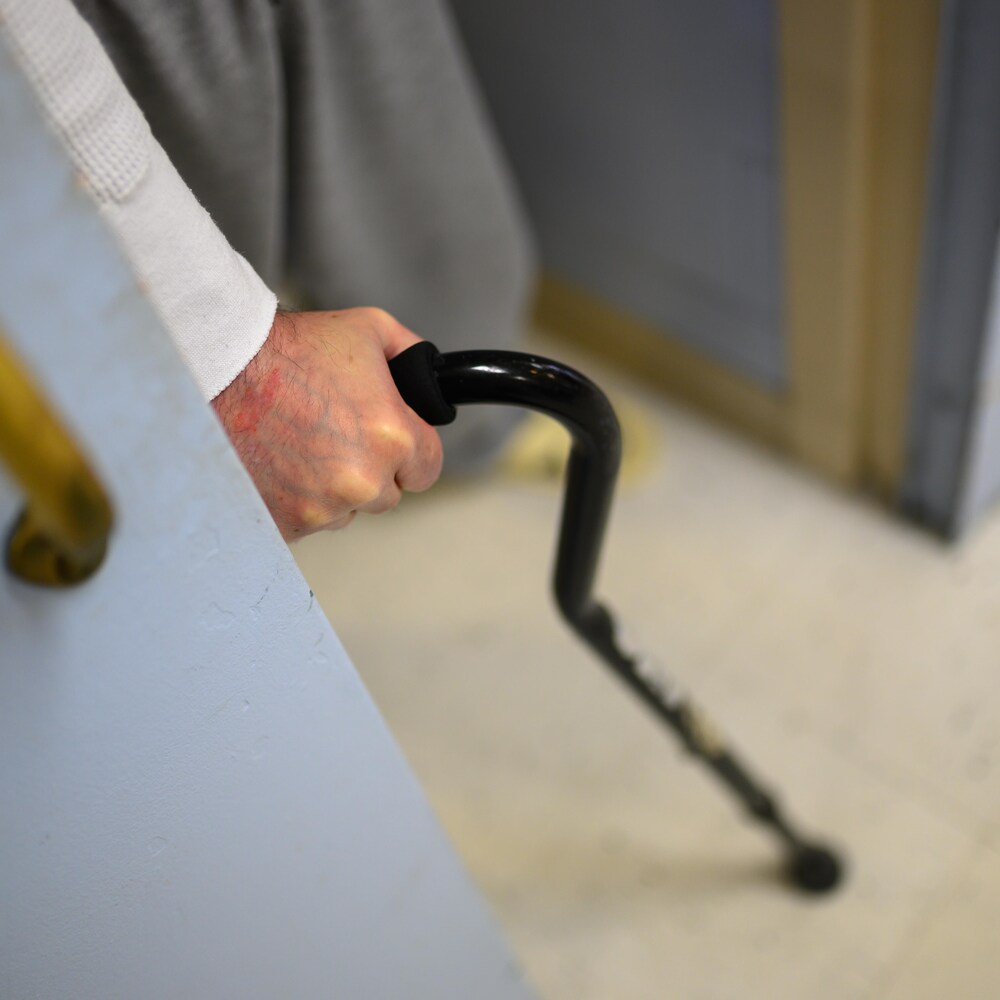 Un détenu sort de sa cellule à l’aide du canne.
