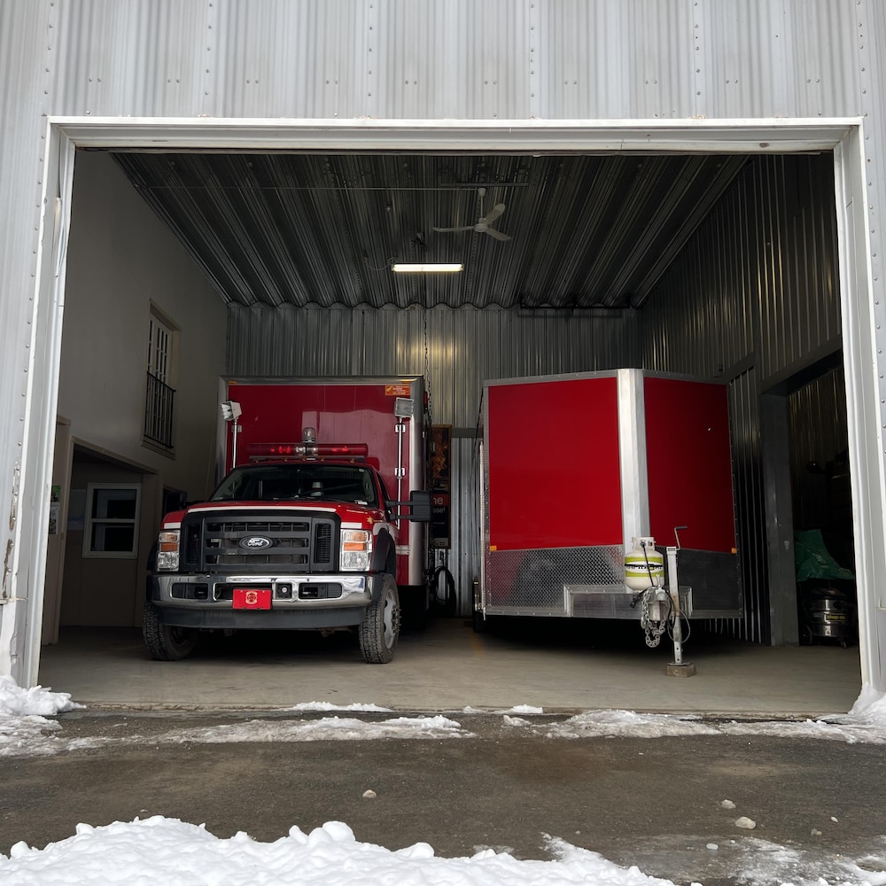 Un camion et une remorque sont stationnés dans un garage dont la porte ouverte.