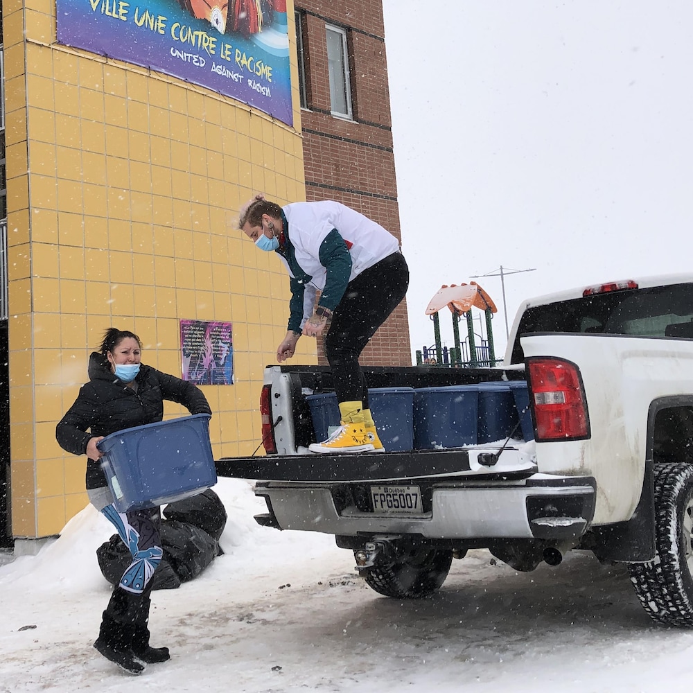 Deux personnes chargent des bacs dans un camion en hiver.