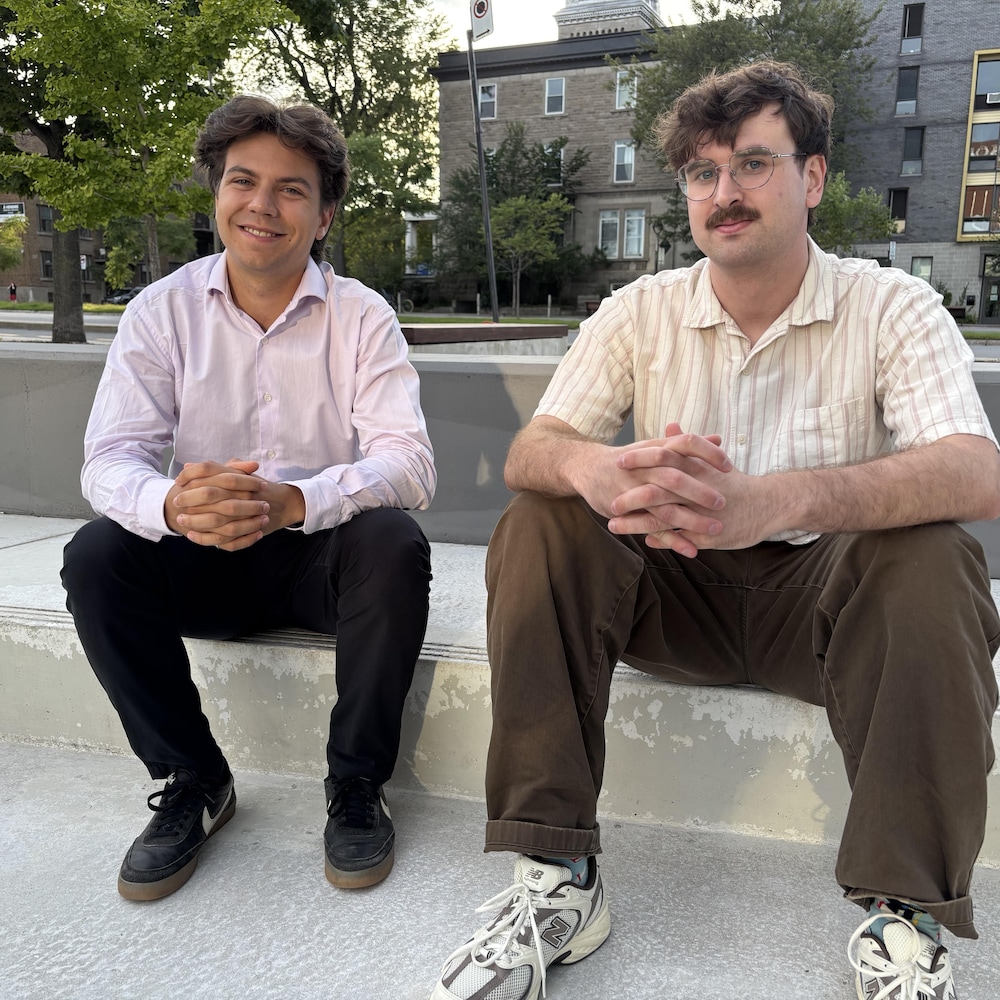 Deux jeunes assis sur un banc de béton à l'extérieur.