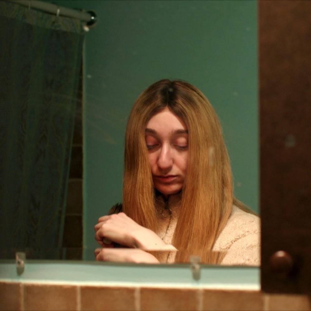 Clara, 24 ans, devant son miroir.