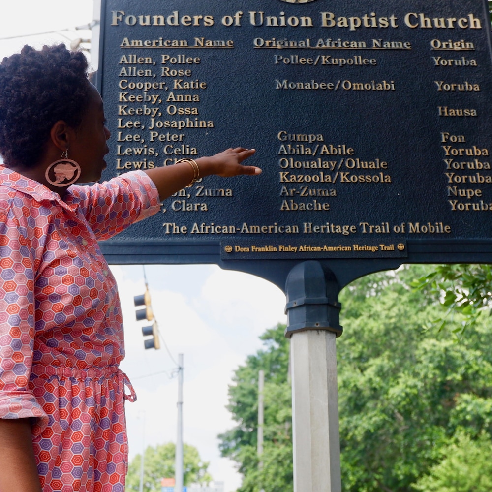 Jocelyn Davis devant une plaque rendant hommage à quelques passagers du Clotilda qui ont fondé une église locale. 