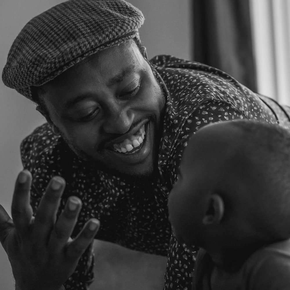 Emmanuel Mbonimpa Rwagasore regarde un jeune enfant en souriant.