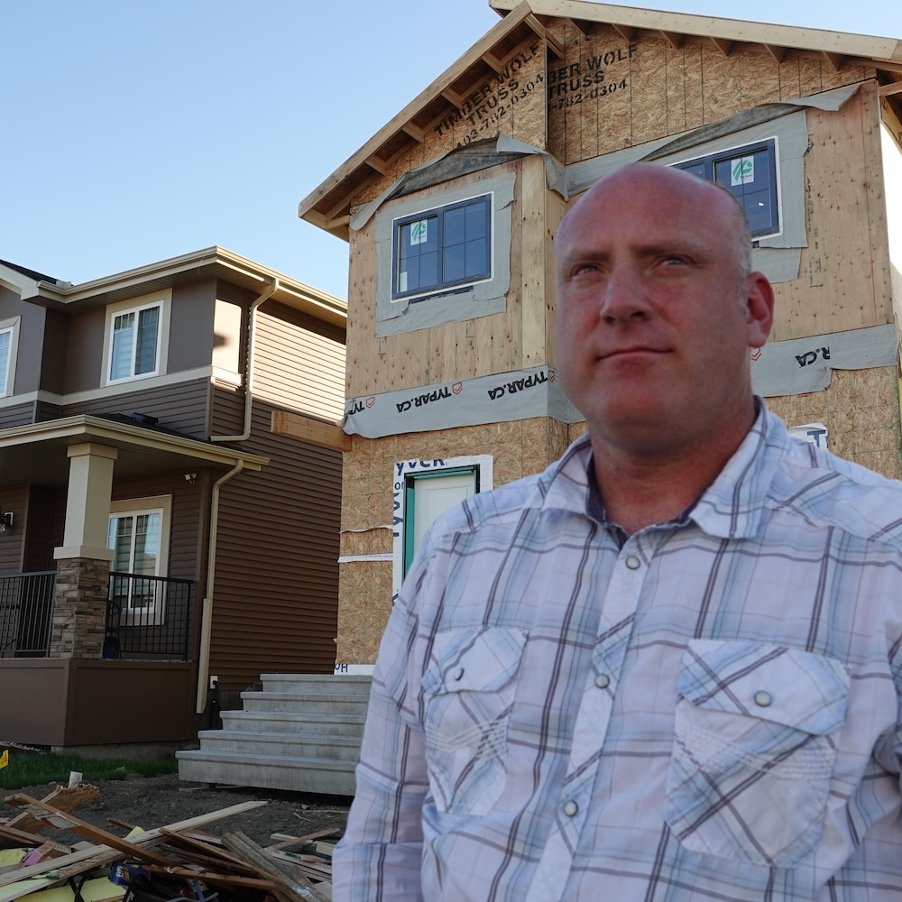 John McKale devant une maison en construction dans un nouveau quartier résidentiel. 