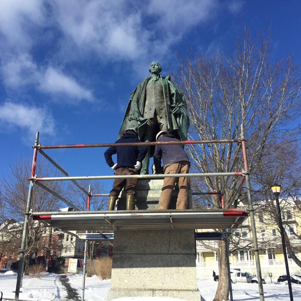 Deux travailleurs sur un échafaudage autour de la statue de Cornwallis.