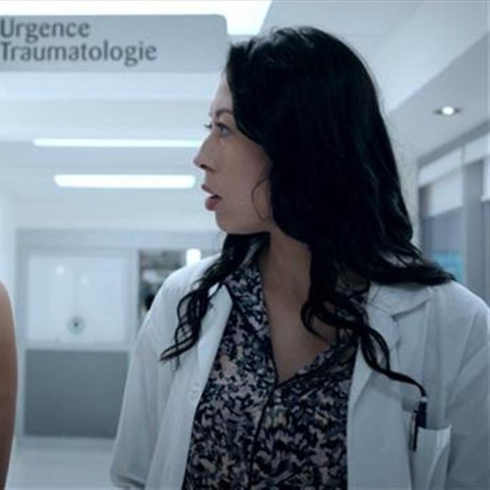 Deux femmes marchent dans un couloir d'hôpital. Une d'entre elle est un médecin et regarde l'autre jeune femme avec un regard inquiet.