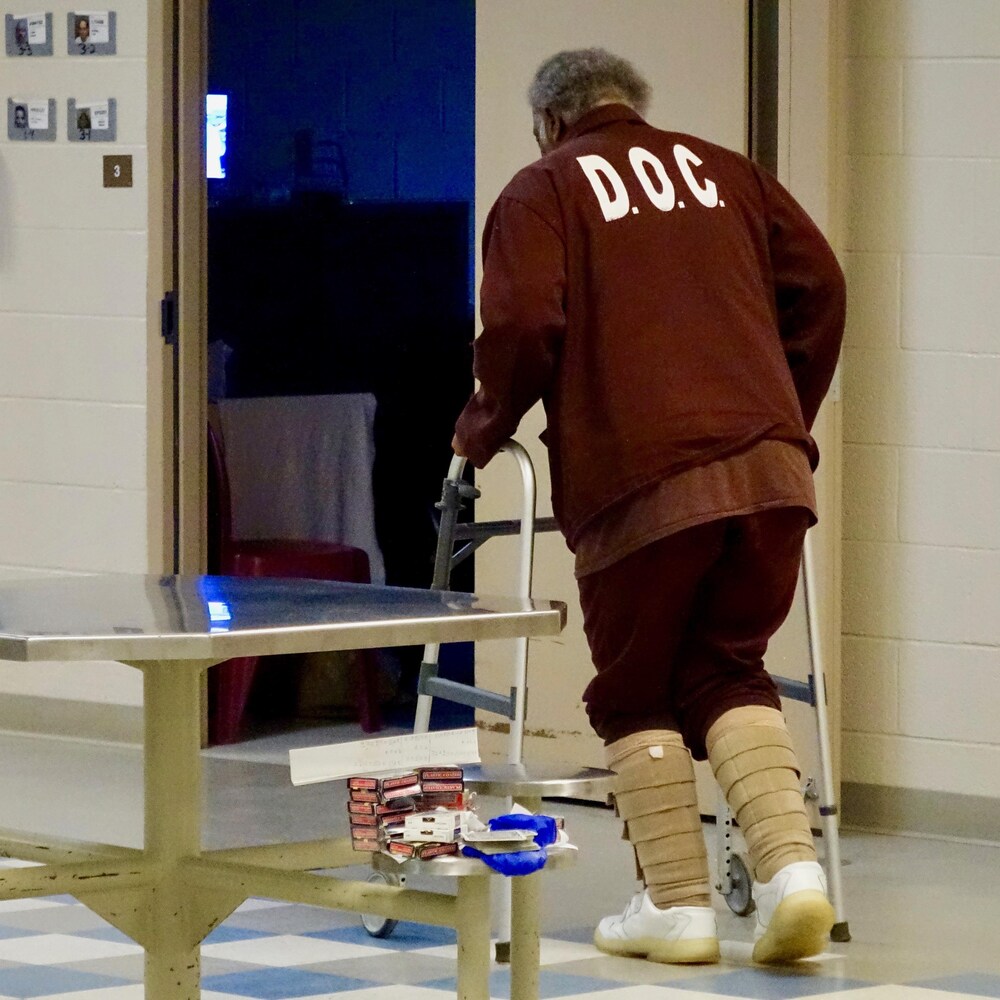 Un prisonnier se déplace à l’aide d’un déambulateur.