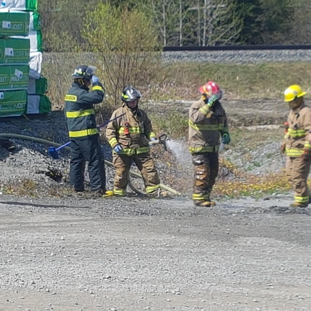Un pompier arrose son collègue avec un boyau d'arrosage.